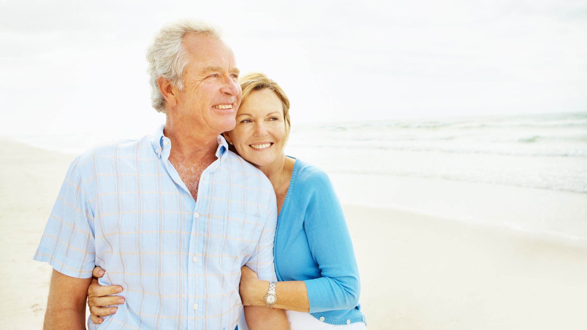 Sweet picture of older couple embracing on a beach